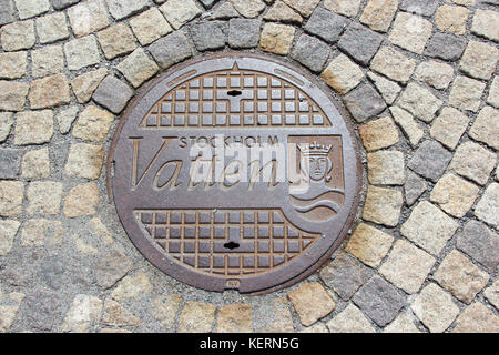 View of the sewer hatch with an inscription on the Swedish "water" on the background of stone paving stones. The center of Stockholm, Sweden. Stock Photo