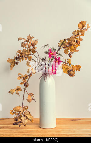 Autumnal ikebana (japanese flower arrangement) with oak tree branches and orchid in a vase Stock Photo