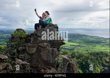 Hiking couple summit Sleeping Giant, a mountain ridge west of Wailua and Kapaa and home of a popular hiking trail on Kauai, Hawaii, United States.