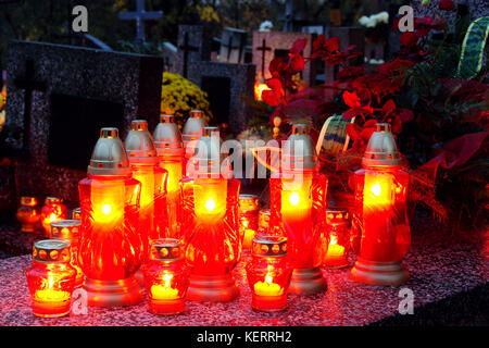 Many glass votive candles lit on tombstone Stock Photo