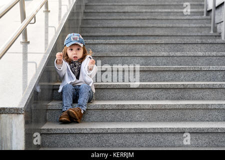 model child hip-hop sitting on stairs outdoor.girl child street fashion jeans clothes Stock Photo