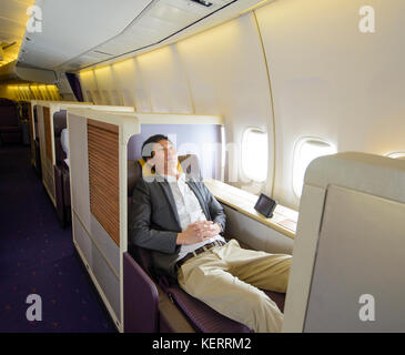 Relaxed mid adult business man sleeping in first class seat Stock Photo