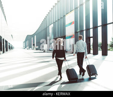 Business people in formal clothing walking in airport terminal with suitcases Stock Photo