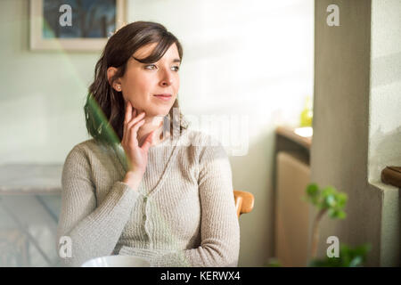 Contemplative Young Adult Woman Looking out Window Stock Photo