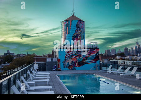 An old water tank and swimming pool on the roof of a luxury Brooklyn apartment building at sunset. Stock Photo