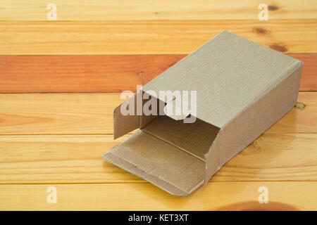 Empty opened brown cardboard box for mock up on bright wooden table with copy space. Stock Photo