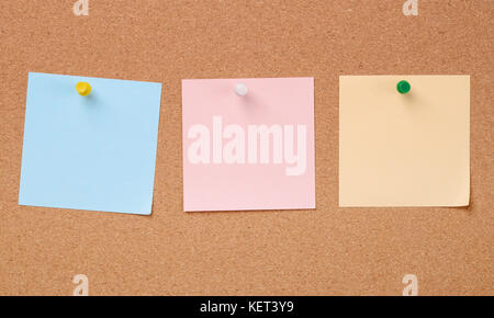 Row of three colors paper notes on cork board Stock Photo