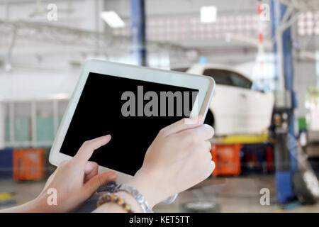 close up asia women using tablet and businesswomen using touch pad and young female mechanic for mechanic inspecting on a car in auto repair shop Stock Photo
