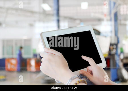close up asia women using tablet and businesswomen using touch pad and young female mechanic for mechanic inspecting on a car in auto repair shop Stock Photo