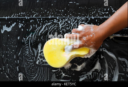 Man washing the car using the yellow sponge with foam . Stock Photo