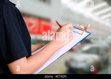 Portrait of smiling young female mechanic inspecting on a car in auto repair shop Stock Photo