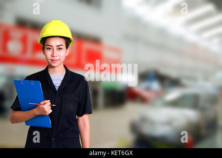 Portrait of smiling young female mechanic inspecting on a car in auto repair shop Stock Photo