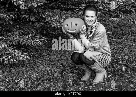 Trick or Treat. Portrait of happy young woman on Halloween at the park with pumpkin Jack O’Lantern Stock Photo