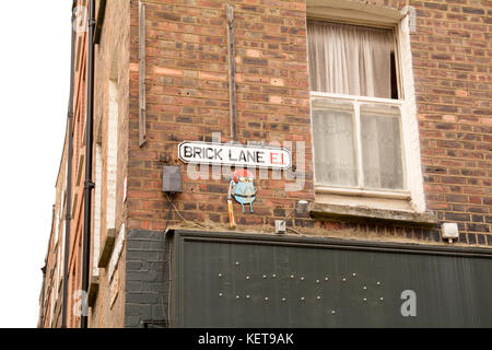 Brick Lane E1 street sign with modern art piece on wall beneath the sign in London England Stock Photo