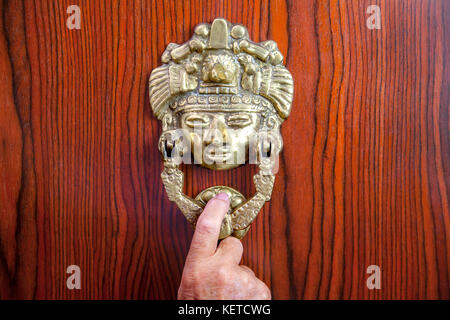 hand on Mexican brass door knocker Stock Photo