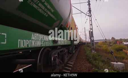 Freight train goes through the bridge. Train or freight train goes on rails. View on freight train rides on the tracks near forest. Railway wagons. Tr Stock Photo