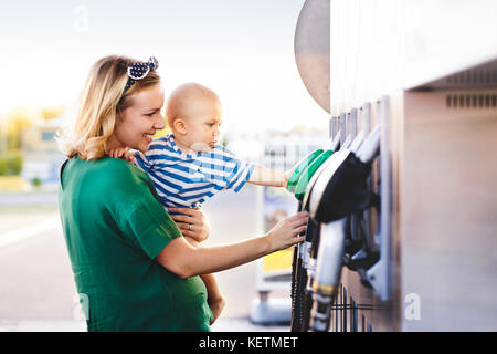 Young mother with baby boy at the petrol station. Stock Photo