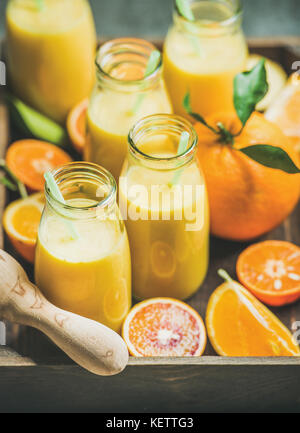 Healthy yellow smoothie in bottles in wooden box