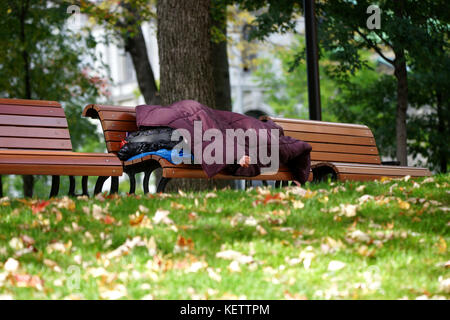 Montreal,Canada,22 October,2017.Homeless man sleeping on a park bench in Montreal's downtown core.Credit:Mario Beauregard/Alamy Live News Stock Photo