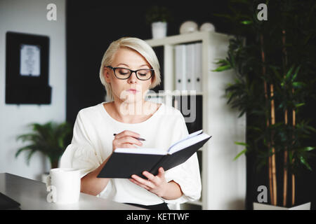 Focused woman writing on a notebook at her office Stock Photo