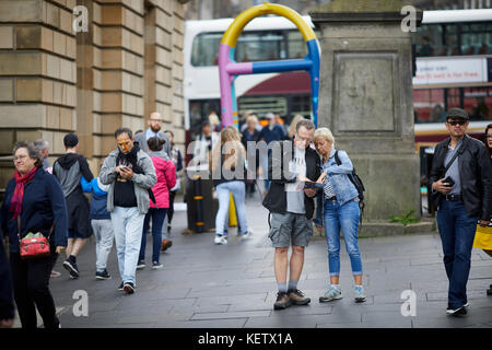 Edinburgh, Scotland, Canongate the Royal Mile lost tourists looking at a map near a painted security barrier Stock Photo