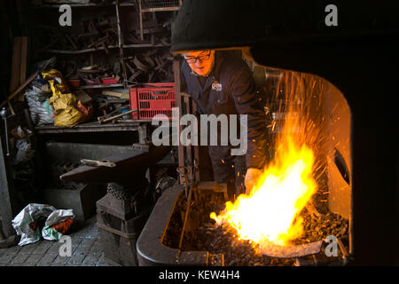 February 10, 2015 - London, United Kingdom - A blacksmith seen working in his workshop..A blacksmith is someone who creates artificial objects from raw iron or steel by forging them to make new creative products such as furniture, agricultural implements, gates, grilles, cooking utensils, railings, light fixtures, sculpture, tools, decorative and religious items, and weapons. Although, there are some more other carriers that are related such as wheelwrights, armors and furriers. The blacksmith has the general knowledge to create and repair many things which has been made with metal, such as th