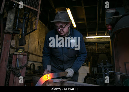 February 10, 2015 - London, United Kingdom - A blacksmith seen working in his studio..A blacksmith is someone who creates artificial objects from raw iron or steel by forging them to make new creative products such as furniture, agricultural implements, gates, grilles, cooking utensils, railings, light fixtures, sculpture, tools, decorative and religious items, and weapons. Although, there are some more other carriers that are related such as wheelwrights, armors and furriers. The blacksmith has the general knowledge to create and repair many things which has been made with metal, such as the 