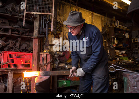 February 10, 2015 - London, United Kingdom - The blacksmith seen working in his studio during a busy workday..A blacksmith is someone who creates artificial objects from raw iron or steel by forging them to make new creative products such as furniture, agricultural implements, gates, grilles, cooking utensils, railings, light fixtures, sculpture, tools, decorative and religious items, and weapons. Although, there are some more other carriers that are related such as wheelwrights, armors and furriers. The blacksmith has the general knowledge to create and repair many things which has been made 