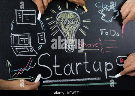 Close-up Of People Working On Startup Plan On Blackboard Stock Photo
