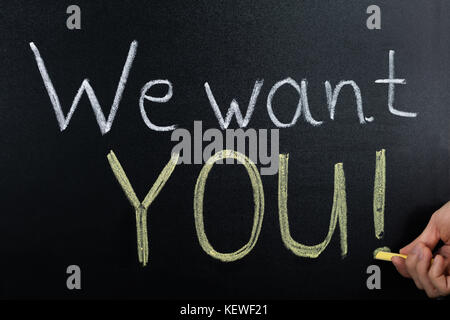 Close-up Of Person Hand With Written Text We Want You On Blackboard Stock Photo
