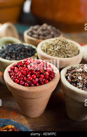 Variety of different spices with focus on pink Peruvian pepper, false pepper used in four peppers blends close up Stock Photo