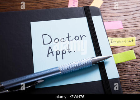 High Angle View Of A Diary Of Doctor Appointment With Sticky Note On Desk Stock Photo