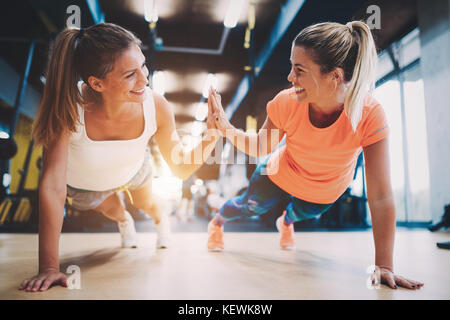 Two sporty girls doing push ups in gym Stock Photo