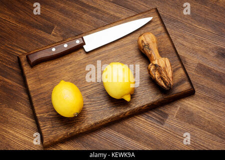Fresh lemon and knife on wooden chopping board Stock Photo