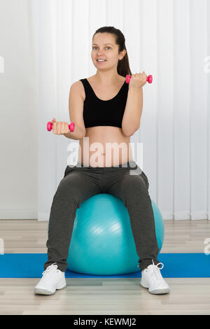 Pregnant Woman Doing Exercise By Sitting On Fitness Ball Stock Photo