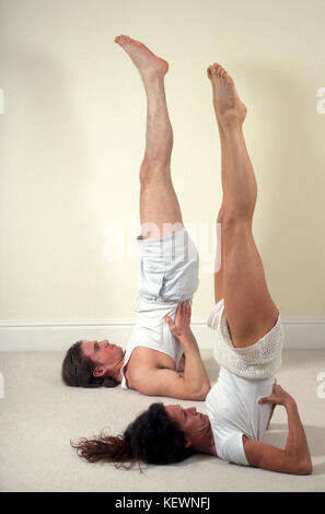 young couple doing yoga shoulders stand Stock Photo