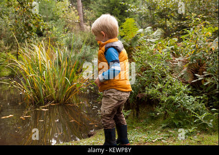 Boy having fun splashing in muddy puddles Stock Photo