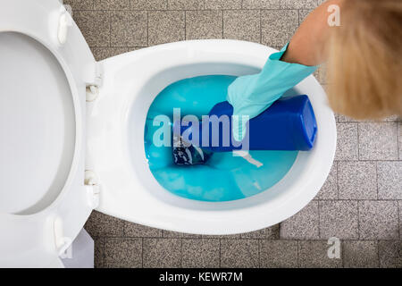 Close-up Of A Person's Hand Wearing Gloves Cleaning Toilet Using Detergent Bottle Stock Photo
