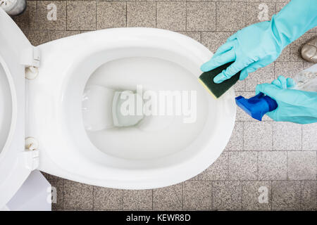 Close-up Of A Person Hand Cleaning Toilet Using Sponge In Bathroom Stock Photo