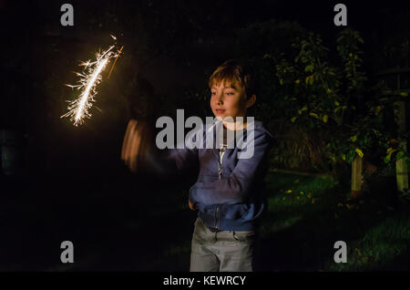 A young boy playing with a sparkler. Stock Photo