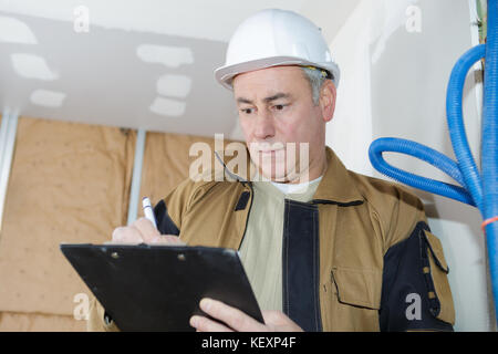 architect checking insulation during house construction Stock Photo