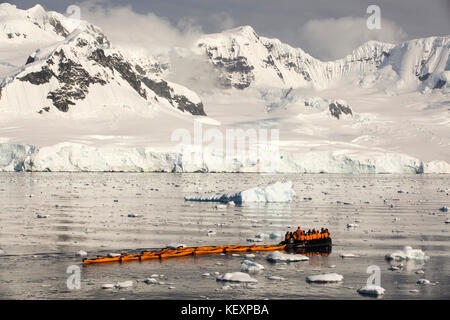 Members of an expedition cruise to Antarctica in a Zodiak with sea kayaks in Fournier Bay in the Gerlache Strait on the Antarctic peninsula. The Antarctic peninsula is one of the most rapidly warming areas on the planet. Stock Photo