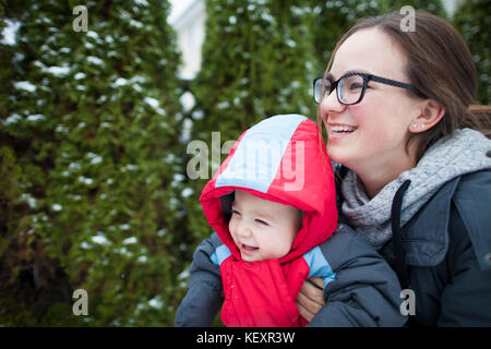 Laughing mother with baby outdoors in winter clothing, Langley, British Columbia, Canada Stock Photo
