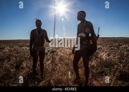 Photograph of two members of San people walking through underbrush in Kalahari Desert, Botswana Stock Photo