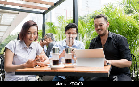Three friends using devices connected to the wireless internet n Stock Photo