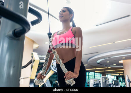 Low-angle view of a beautiful woman exercising cable rope tricep Stock Photo