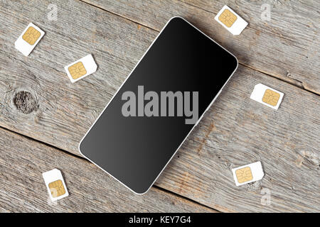 Smartphone with blank screen and SIM cards on the table, top view Stock Photo