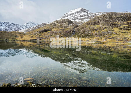 Crib Goch (Red ridge) part of the Snowdon horseshoe reflected in Llyn Llydaw with Mount Snowdon summit in the background Snowdonia National Park Stock Photo