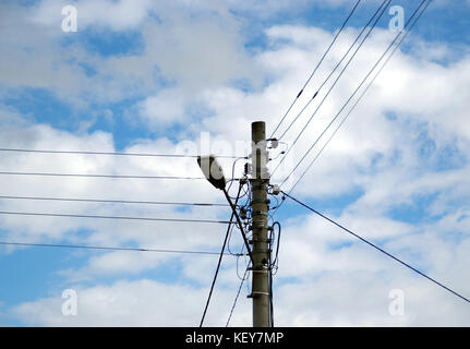 Street lamp pole with wires and cables on cloudy sky background. Stock Photo