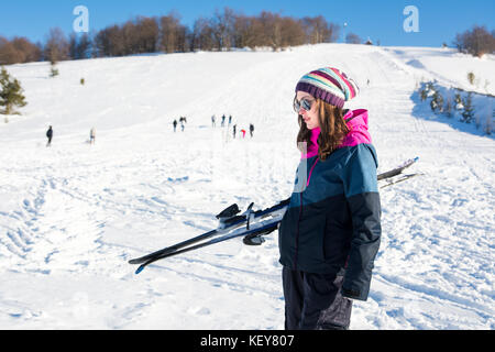 Girl holding skis on a snowy mountain on a sunny day Stock Photo